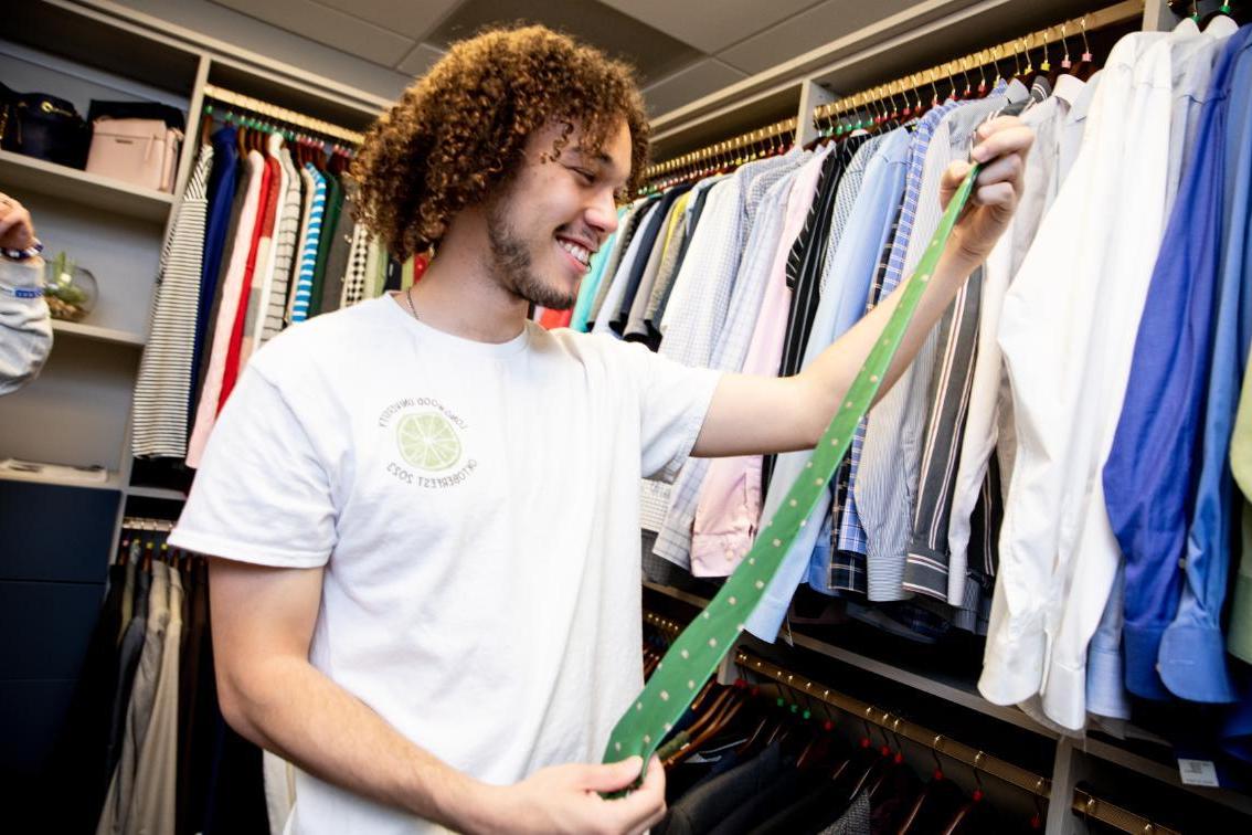 Student looking at a tie in the Career Closet